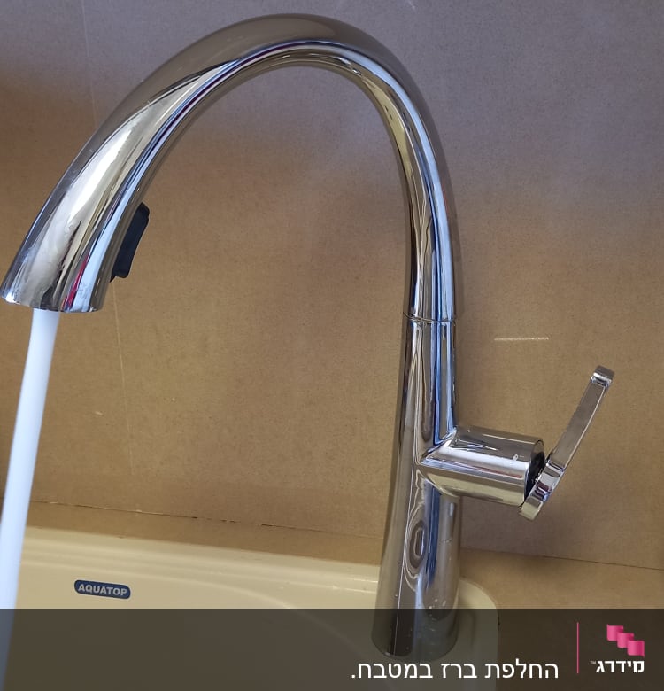 ברז נירוסטה עם מים זורמים בכיור מטבח